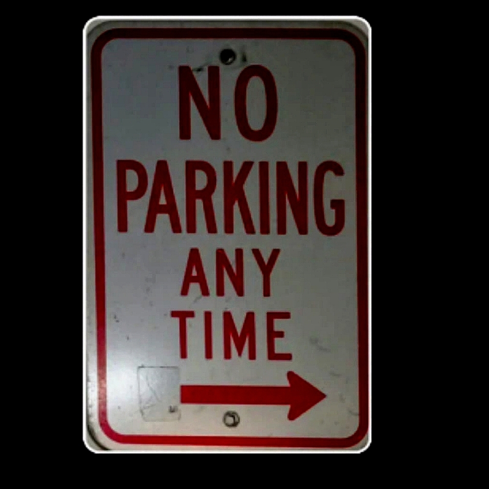 A metal sign that says NO PARKING... ANY TIME w/ red arrow Pointing That Way -->